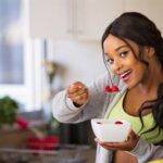 Breast Cancer and Diet: What's the Connection? - Young woman eating a bowl of Strawberries